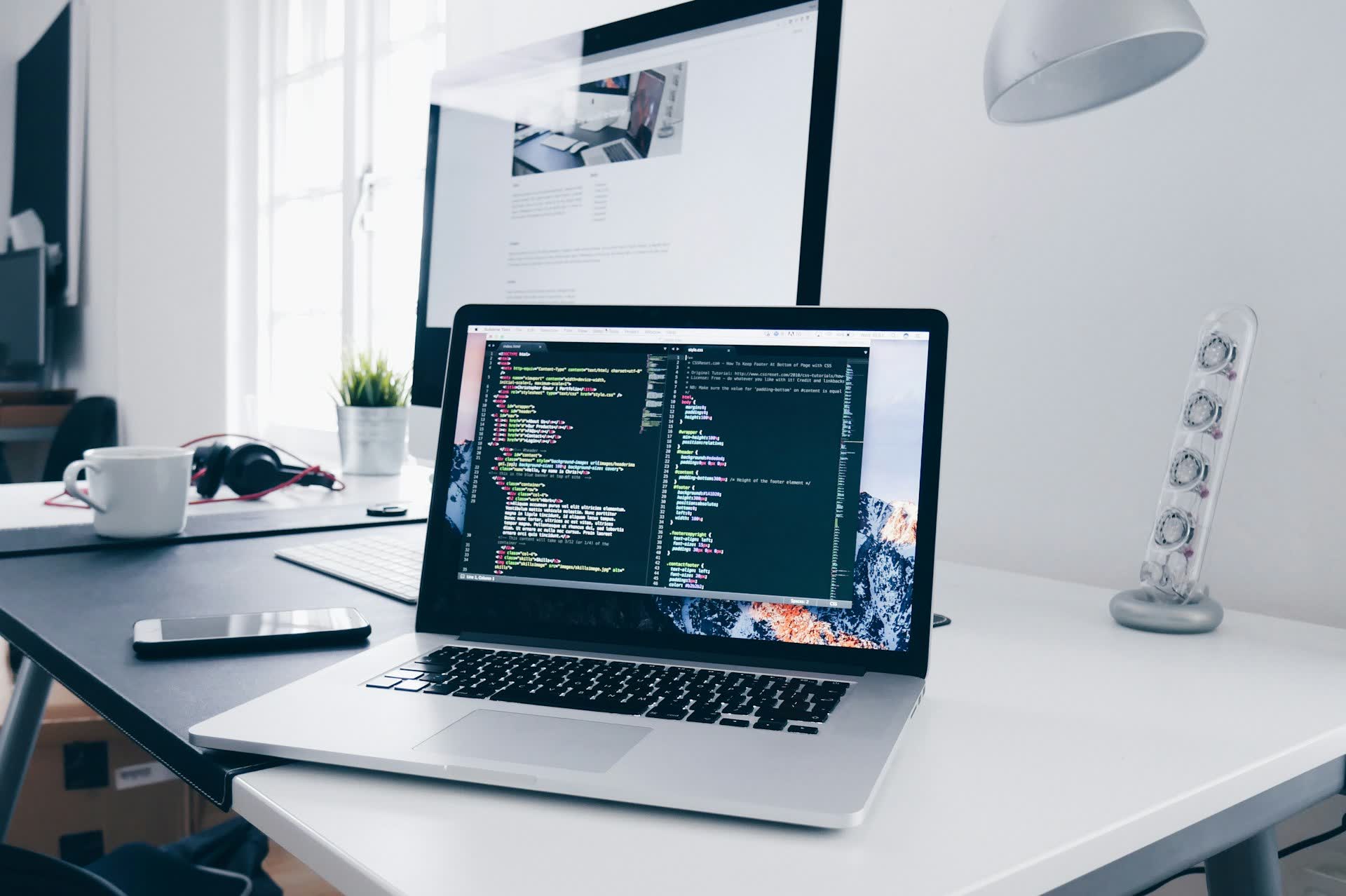 Developer workspace with multiple screens showing code and modern UI - dark cinematic lighting