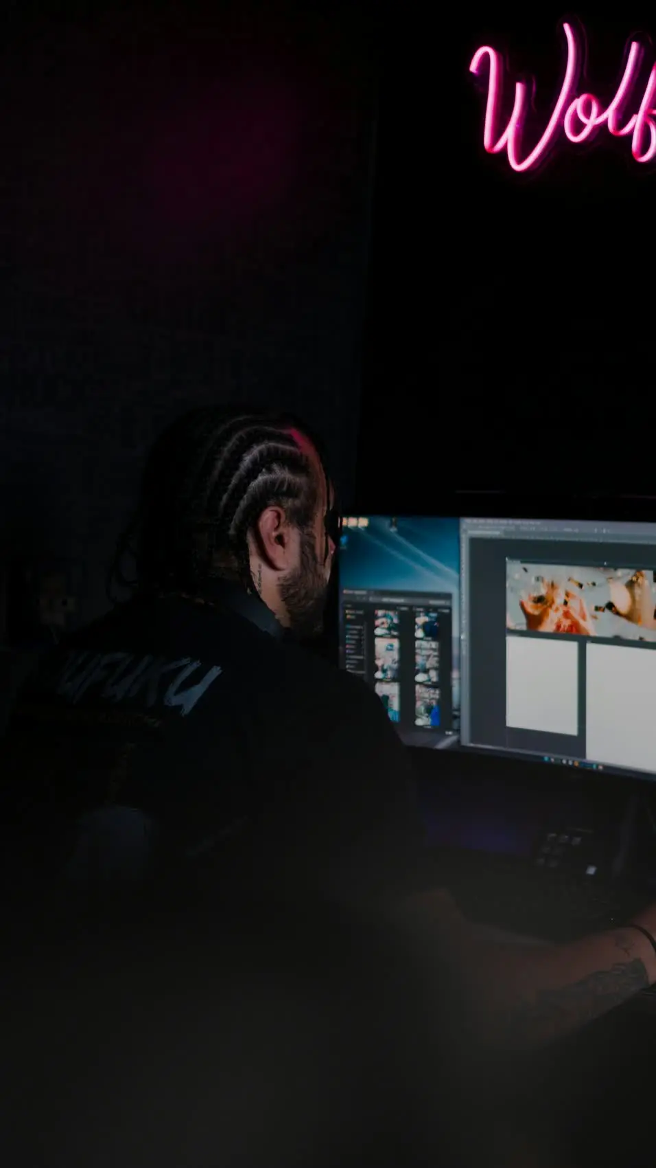 Creative professional working at computer with neon studio lighting - content creation